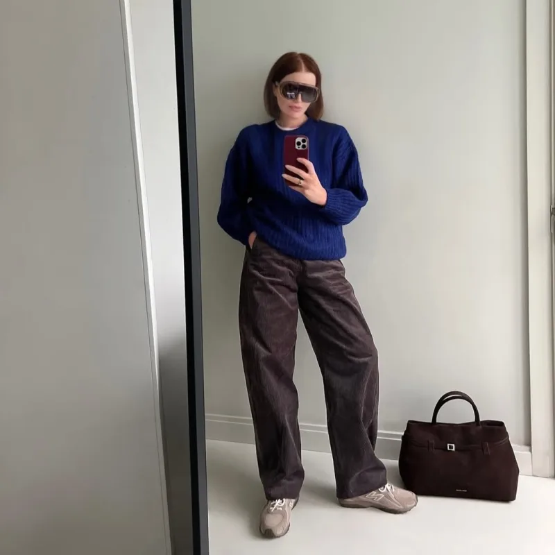 Influencer με μπλε πουλόβερ, καφέ κοτλέ παντελόνι και sneakers.