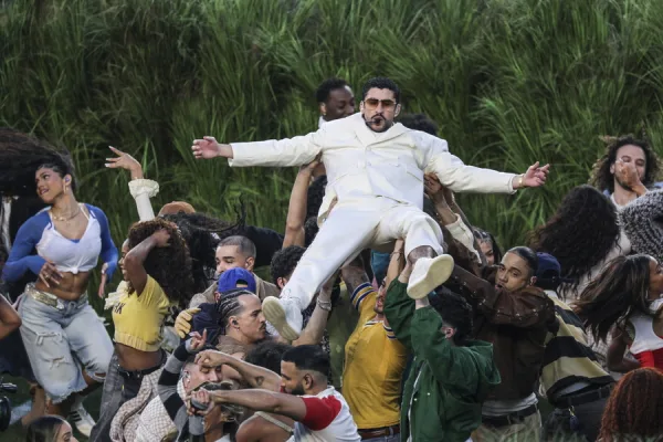 Ο Bad Bunny σηκώνεται από το πλήθος φορώντας λευκό κοστούμι, κατά τη διάρκεια μιας εμφάνισης που σχετίζεται με το Super Bowl.