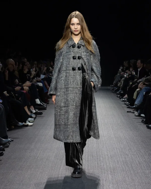 Μοντέλο στην πασαρέλα του οίκου Emporio Armani με γκρι παλτό και μαύρο παντελόνι.