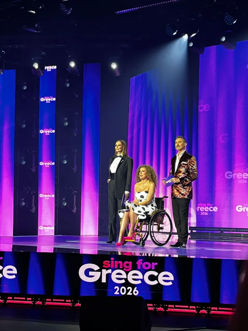 Οι παρουσιαστές του Sing for Greece 2026, η μία σε αναπηρικό αμαξίδιο, στην εντυπωσιακή έναρξη του Β' Ημιτελικού.