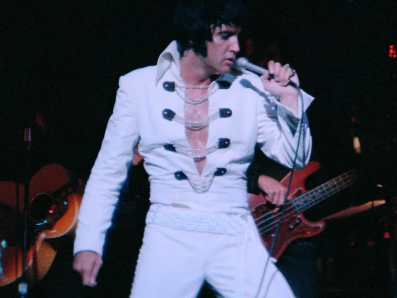 Ο Elvis Presley στη σκηνή με λευκή ολόσωμη φόρμα.