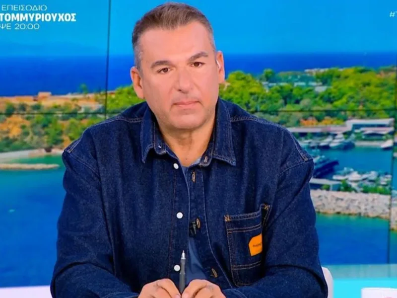 Ο Γιώργος Λιάγκας σε πλάνο από την εκπομπή Πρωινό, με φόντο τοπίο με θάλασσα και βουνό.