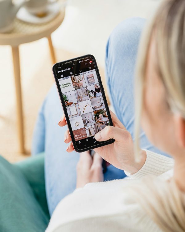 Γυναίκα κρατάει smartphone και κάνει σκρολάρισμα στο Instagram.