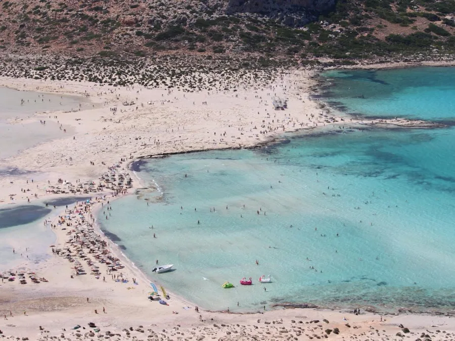 Πανοραμική άποψη της παραλίας Ελαφονήσι στην Κρήτη με γαλαζοπράσινα νερά και λευκή άμμο.