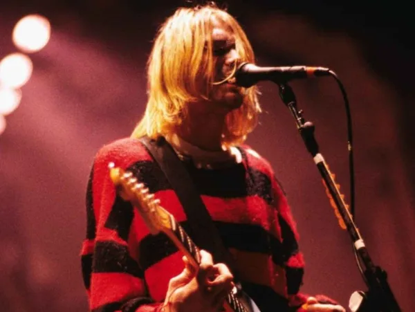 Ο Kurt Cobain στη σκηνή με κιθάρα και ριγέ πουλόβερ
