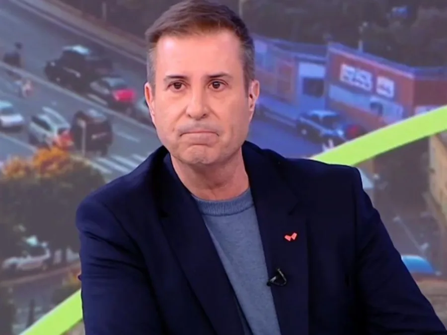Ο Παναγιώτης Στάθης σε τηλεοπτικό πλατό με σοβαρή έκφραση.