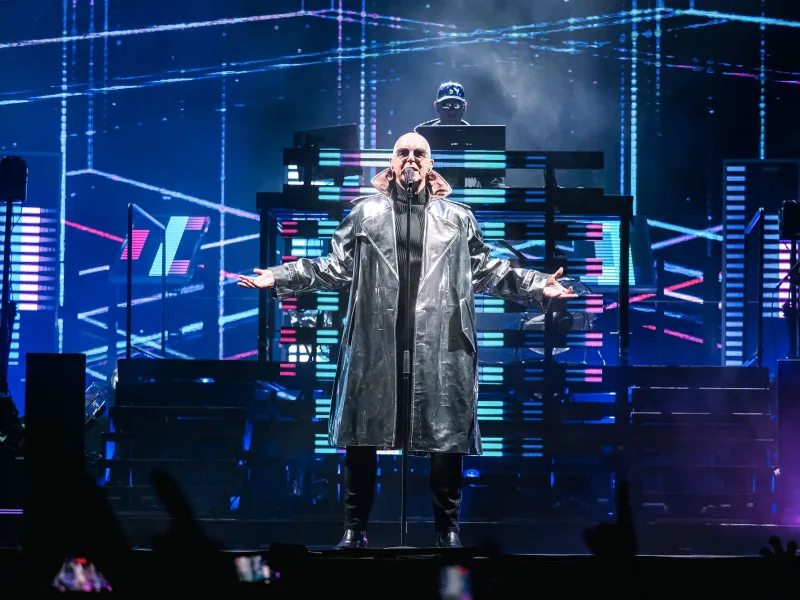 Ο Neil Tennant των Pet Shop Boys στη σκηνή με ασημί παλτό.