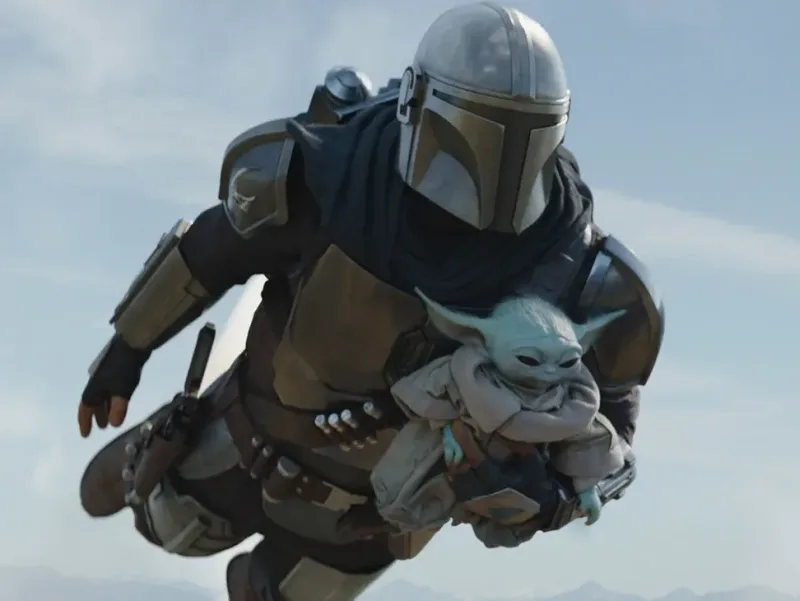 Ο Mandalorian πετάει στον αέρα κρατώντας τον Grogu.
