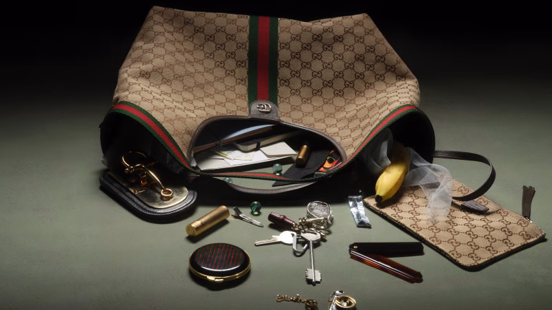 Η τσάντα Gucci Giglio με το χαρακτηριστικό μονόγραμμα GG και τις πράσινες-κόκκινες ρίγες, περιέχει διάφορα αντικείμενα.