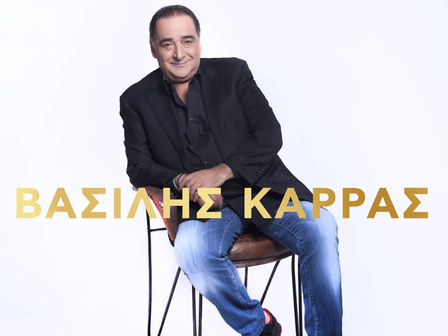Ο Βασίλης Καρράς καθισμένος σε σκαμπό