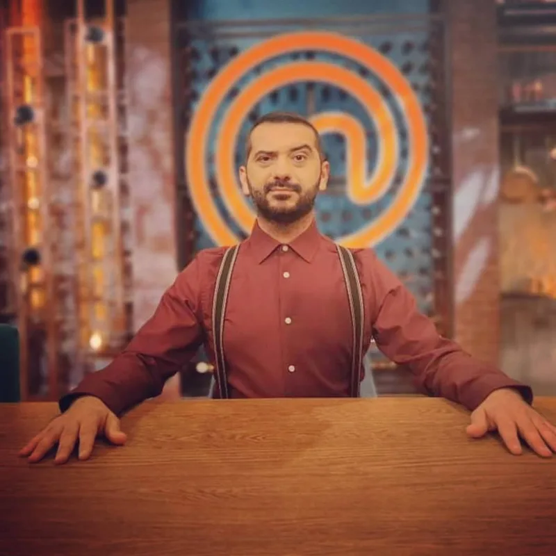 Ο Λεωνίδας Κουτσόπουλος στο MasterChef, τη στιγμή που μιλάει για τη Χρύσα Μιχαλοπούλου, φορώντας κόκκινο πουκάμισο.