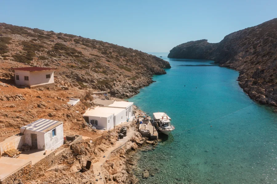 Παραθαλάσσιος οικισμός με λευκά σπίτια και σκάφη σε γαλαζοπράσινα νερά.