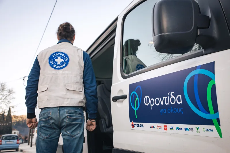 Άνδρας των Γιατρών του Κόσμου δίπλα σε βαν με το λογότυπο Φροντίδα για όλους και Motor Oil.