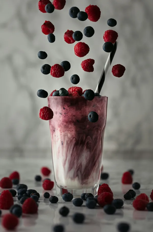 Κρεμώδες smoothie με superfoods, βατόμουρα και σμέουρα να πέφτουν μέσα στο ποτήρι, ιδανικό για ενέργεια.