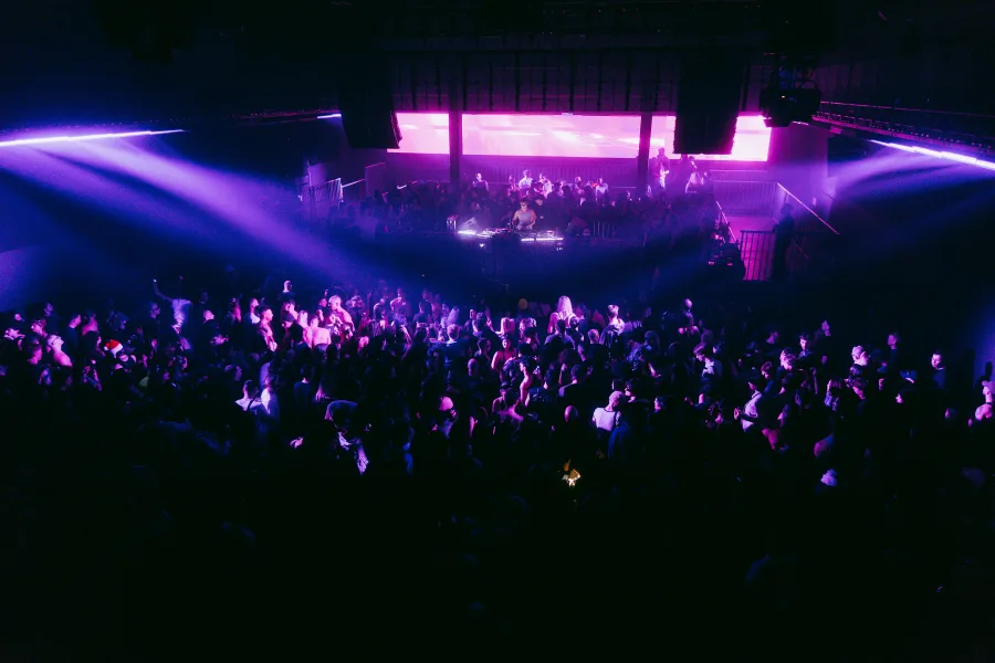 Πλήθος κόσμου σε rave πάρτι στο Universe Athens με μοβ φωτισμό.