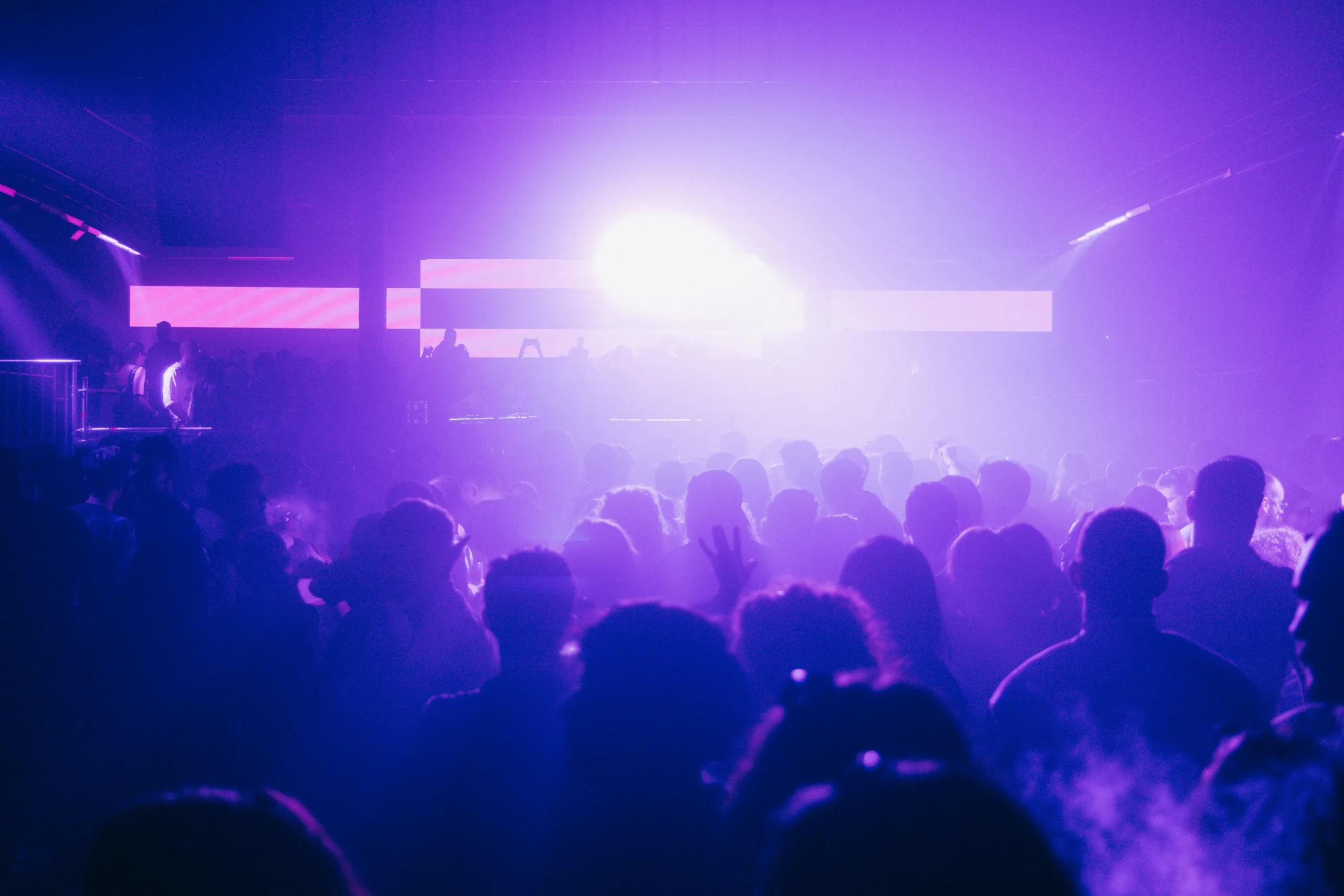Πλήθος κόσμου σε rave party στο Universe Athens με έντονο μωβ φωτισμό.