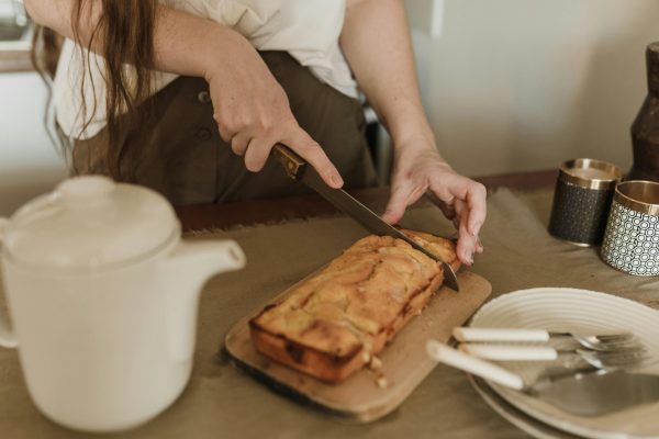 Χέρια κόβουν αλμυρό cake με 5 υλικά σε ξύλο κοπής, έτοιμο για σερβίρισμα.