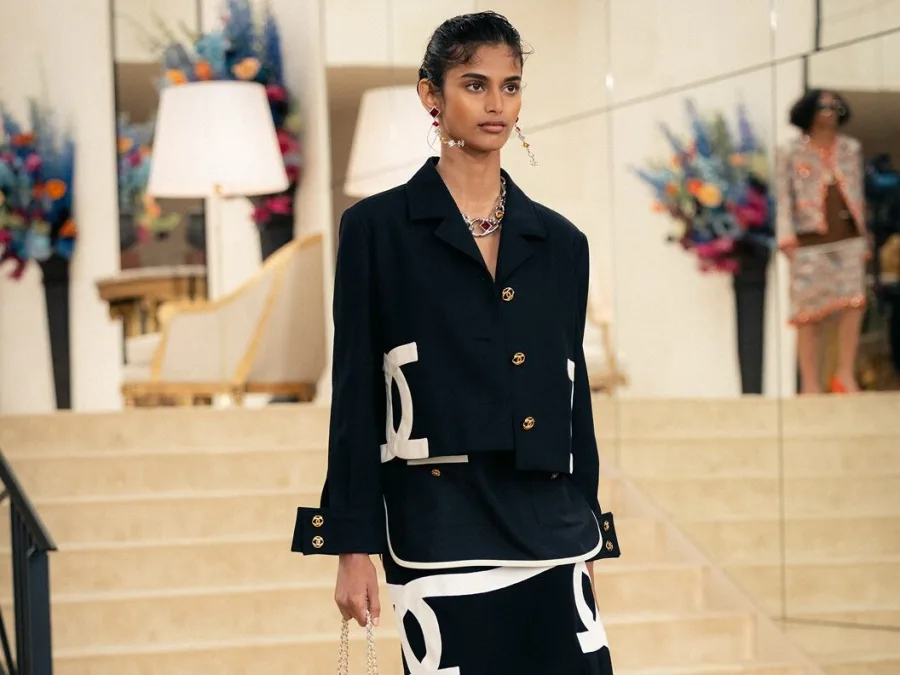 Μοντέλο στην επίδειξη μόδας Chanel Cruise 2027 με μαύρο ταγιέρ και λευκά σχέδια.