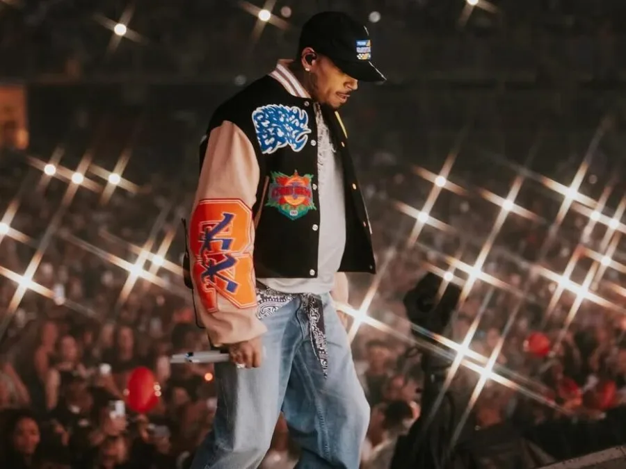 Ο Chris Brown στη σκηνή με varsity jacket και καπέλο.