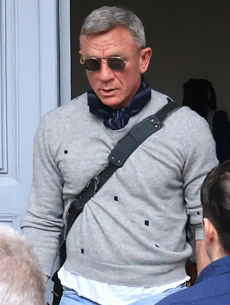 Ο Daniel Craig με γυαλιά ηλίου και κασκόλ στα γυρίσματα στην Αθήνα, φορώντας γκρι πουλόβερ.
