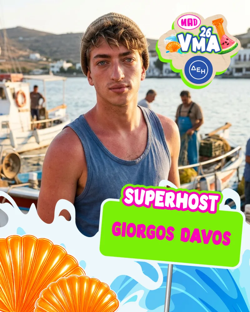 Ο Γιώργος Νταβός, Superhost των Mad VMA 2026, ποζάρει με φόντο λιμάνι και σκάφη, προετοιμάζοντας το κοινό για τη βραδιά.