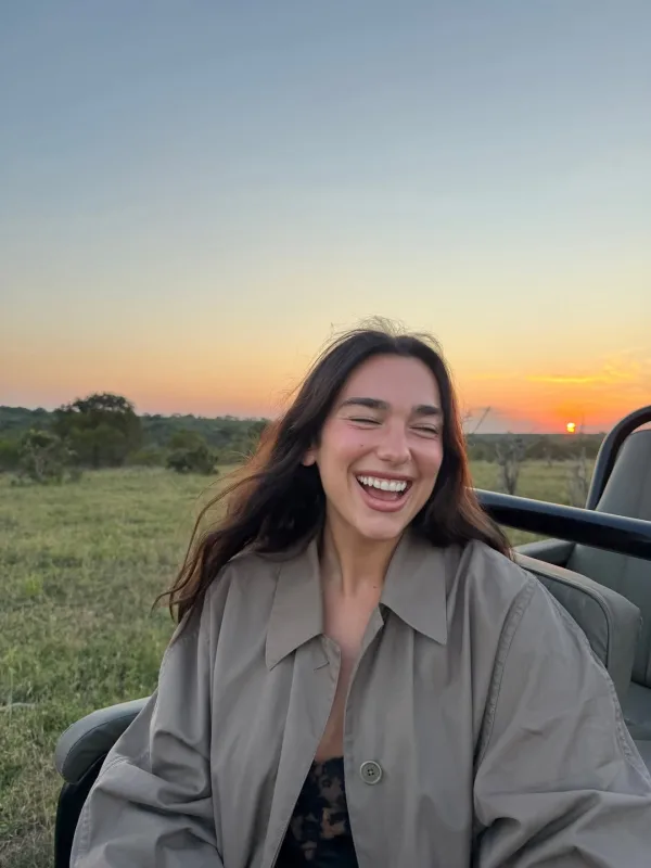 Η Dua Lipa απολαμβάνει ένα χαρούμενο ηλιοβασίλεμα κατά τη διάρκεια σαφάρι στη Νότια Αφρική, με φόντο την άγρια φύση.
