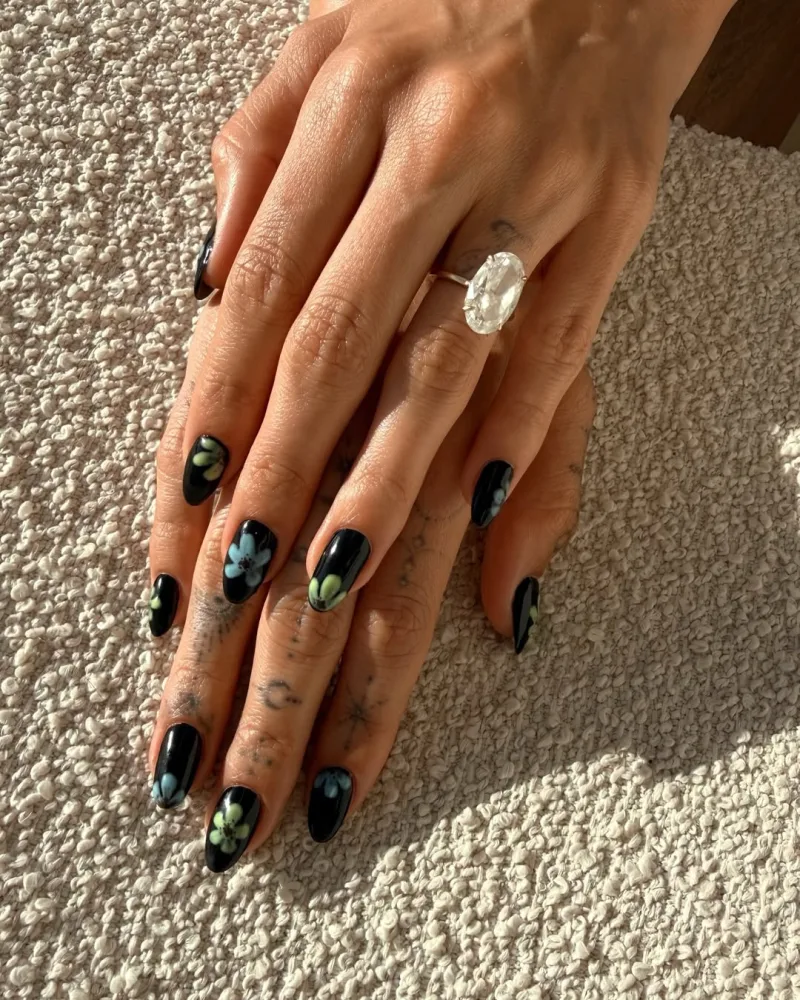 Hailey Bieber δείχνει το νέο της μανικιούρ με μαύρο βερνίκι και λουλούδια, υιοθετώντας το anti-trend της άνοιξης.