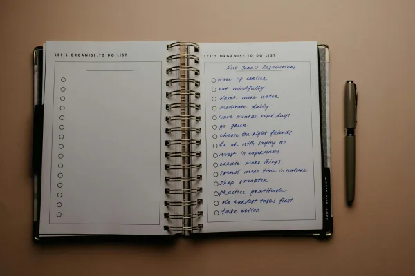 Ανοιχτό bullet journal με λίστα "New Year's Resolutions" και στυλό δίπλα, ιδανικό για οργάνωση ζωής.