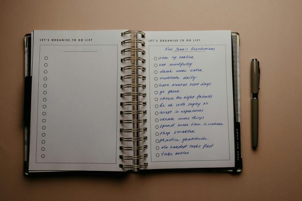 Ανοιχτό bullet journal με λίστα "New Year's Resolutions" και στυλό δίπλα, ιδανικό για οργάνωση ζωής.