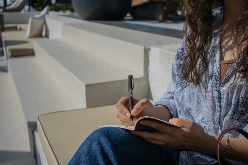 Γυναίκα γράφει σε bullet journal για να βάλει τάξη στη ζωή της, ακολουθώντας τον απόλυτο οδηγό για αρχάριους.