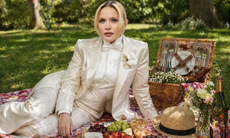 Η pop star Madonna απολαμβάνει ένα πικνίκ στα ελληνικά λιβάδια, φορώντας ένα κομψό λευκό κοστούμι.
