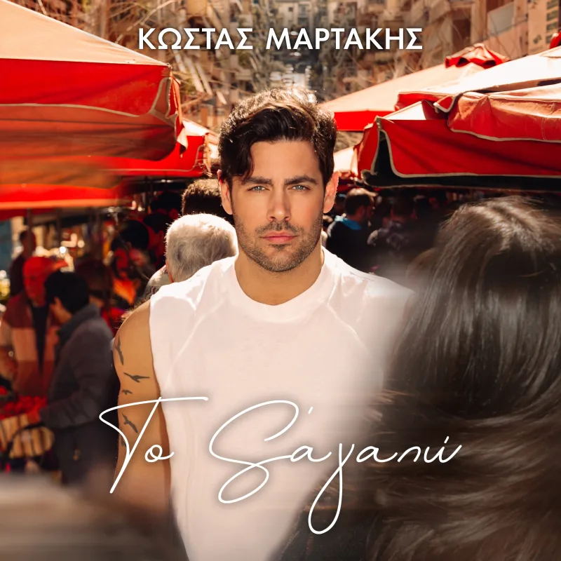 Ο Κώστας Μαρτάκης ποζάρει με λευκό t-shirt σε υπαίθρια αγορά για τη νέα εκτέλεση του τραγουδιού «Σ’ αγαπώ».