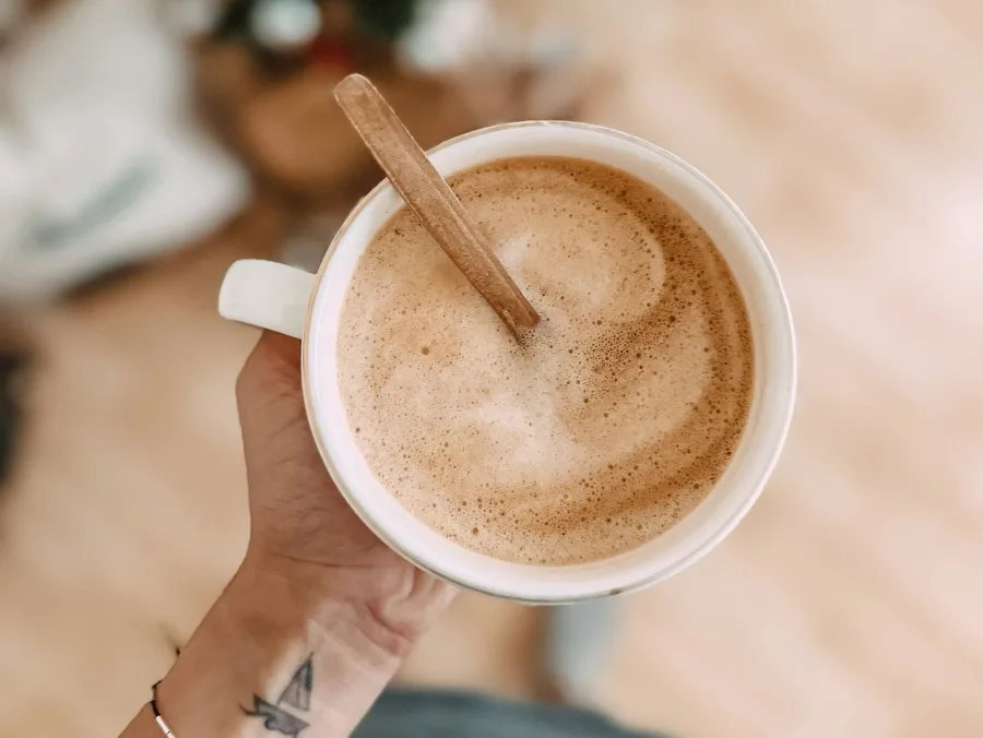 Ένα φλιτζάνι Nordic Latte με ξύλινο αναδευτήρα, ένα πράσινο ρόφημα που αποτοξινώνει δέρμα και σώμα.