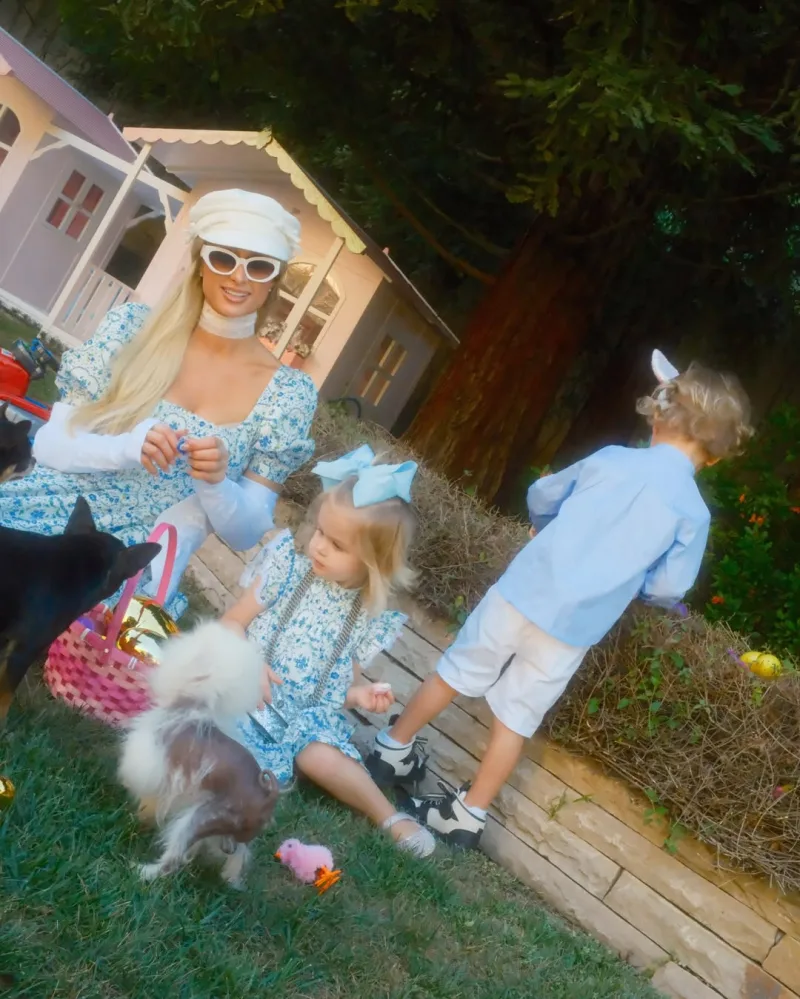 Η Paris Hilton με τα παιδιά της και τους σκύλους τους απολαμβάνουν το πασχαλινό κυνήγι αυγών στο γρασίδι.