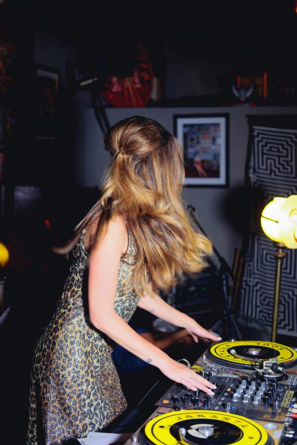 Μια γυναίκα DJ με λεοπάρ φόρεμα παίζει μουσική σε ένα πάρτι, αποδεικνύοντας ποια ζώδια είναι τα πιο party animals.