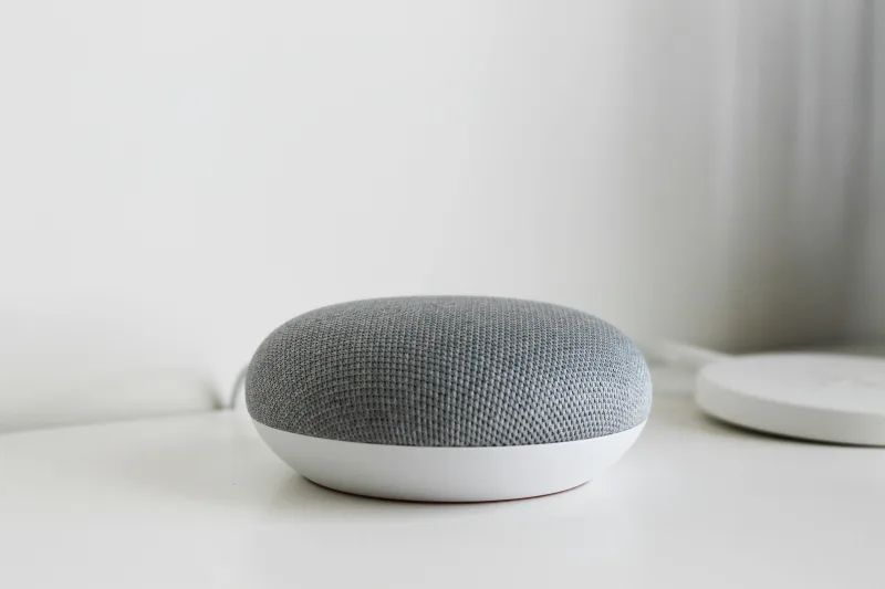 Έξυπνο ηχείο Google Home Mini σε λευκή επιφάνεια, μέρος της τεχνολογίας AI για κατοικίδια.