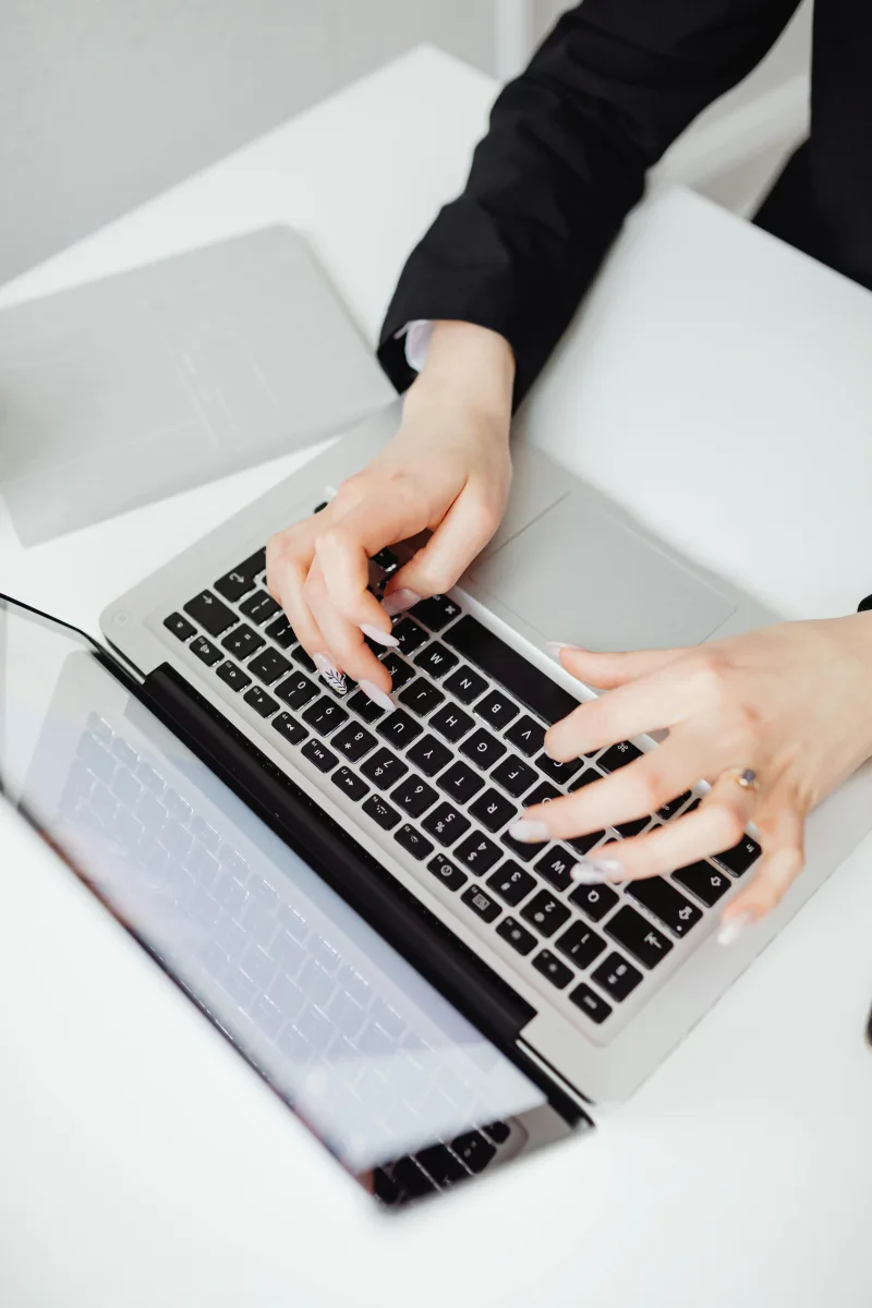 Γυναίκα με μαύρο σακάκι πληκτρολογεί σε laptop, ετοιμάζοντας την καριέρα της για την αγορά εργασίας.