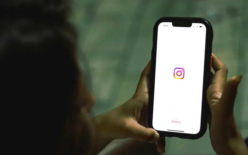 Χρήστης κρατάει smartphone με ανοιχτή την εφαρμογή Instagram, εστιάζοντας στα digital red flags που αναφέρονται στο άρθρο.