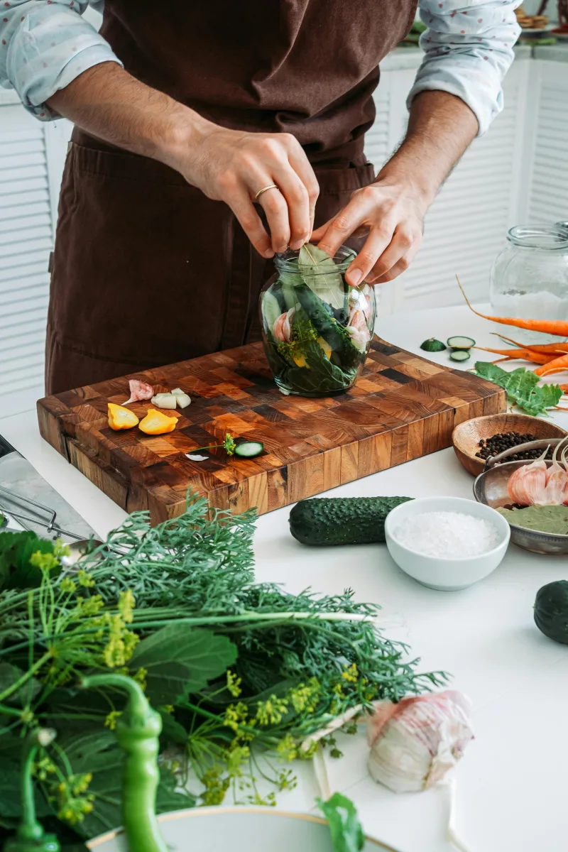 Άνδρας ετοιμάζει Mason Jar Salads με φρέσκα λαχανικά, σκόρδο και μπαχαρικά για ένα υγιεινό γεύμα.