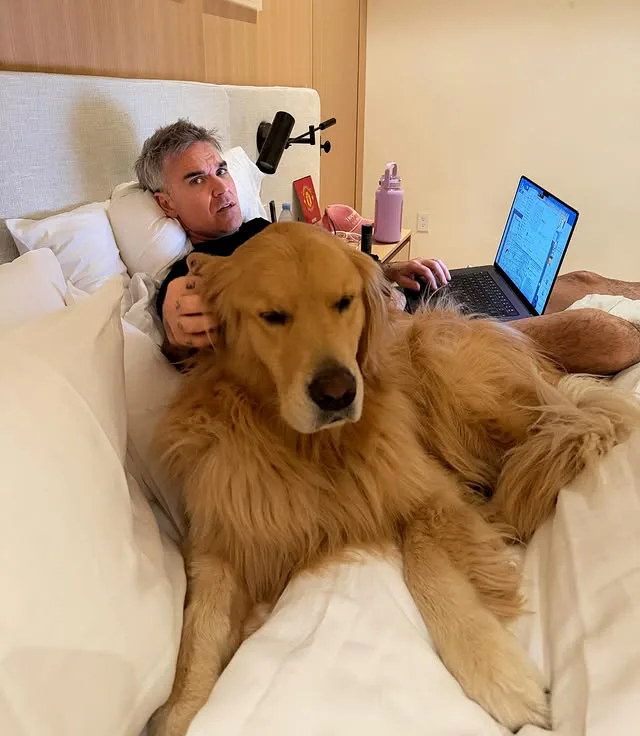 Ο Robbie Williams ξαπλωμένος στο κρεβάτι με τον σκύλο του, συζητώντας για το μέλλον της μουσικής και τον ρόλο του AI.
