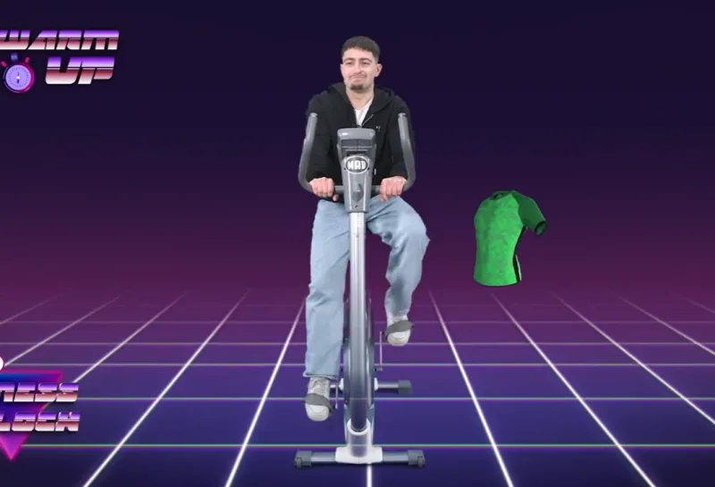 Ο Γιώργος Αυλωνίτης στο Fitness O' Clock κάνει ποδήλατο, ενώ δίπλα του βρίσκεται μια πράσινη μπλούζα.
