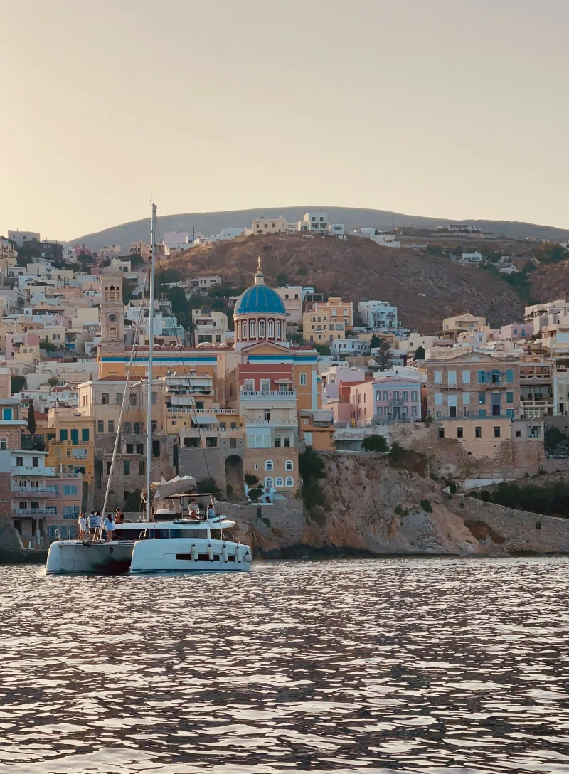 Καταμαράν με επιβάτες αγκυροβολημένο μπροστά από την Ερμούπολη, έναν από τους ελληνικούς προορισμούς για αξέχαστο Πάσχα.