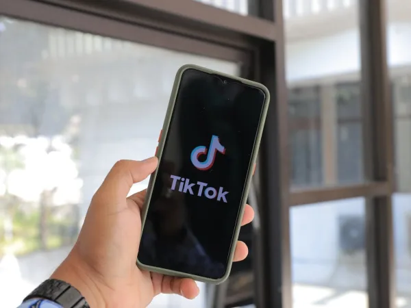 Χέρι κρατάει smartphone με το λογότυπο του TikTok, αναδεικνύοντας την πλατφόρμα που προκάλεσε viral χάος.