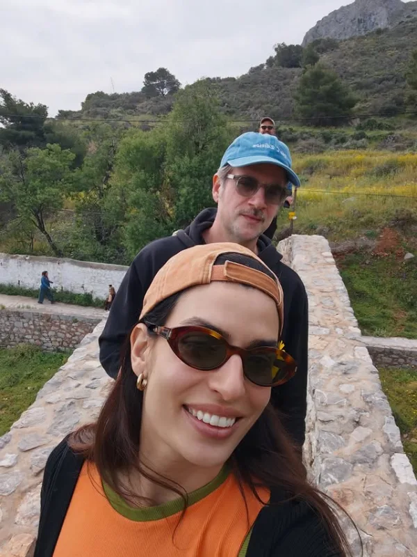 Η Τόνια Σωτηροπούλου γιορτάζει τα γενέθλιά της με τον σύντροφό της σε εξωτερικό χώρο με πέτρινη γέφυρα.