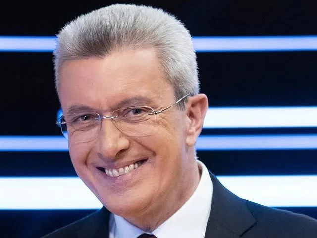 Ο Νίκος Χατζηνικολάου χαμογελάει στην κάμερα φορώντας γυαλιά και κοστούμι, μετά από επέμβαση στα μαλλιά.