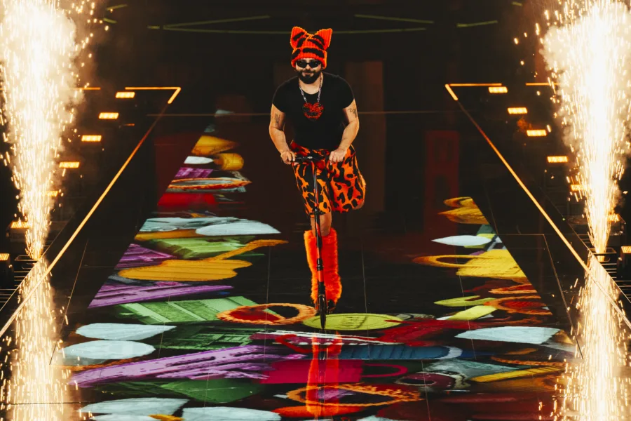 Ο Ακύλας στη σκηνή της Eurovision 2026 με πατίνι και πορτοκαλί αξεσουάρ.