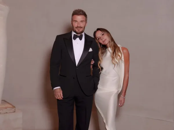 Victoria Beckham και David Beckham ποζάρουν μαζί, με την Victoria να έχει ακουμπήσει το κεφάλι της στον ώμο του David.