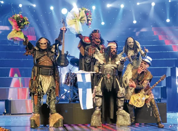 Οι Lordi στον τελικό της Eurovision 2026 με τη σημαία της Φινλανδίας και μπουκέτα λουλουδιών, κρατώντας όργανα.