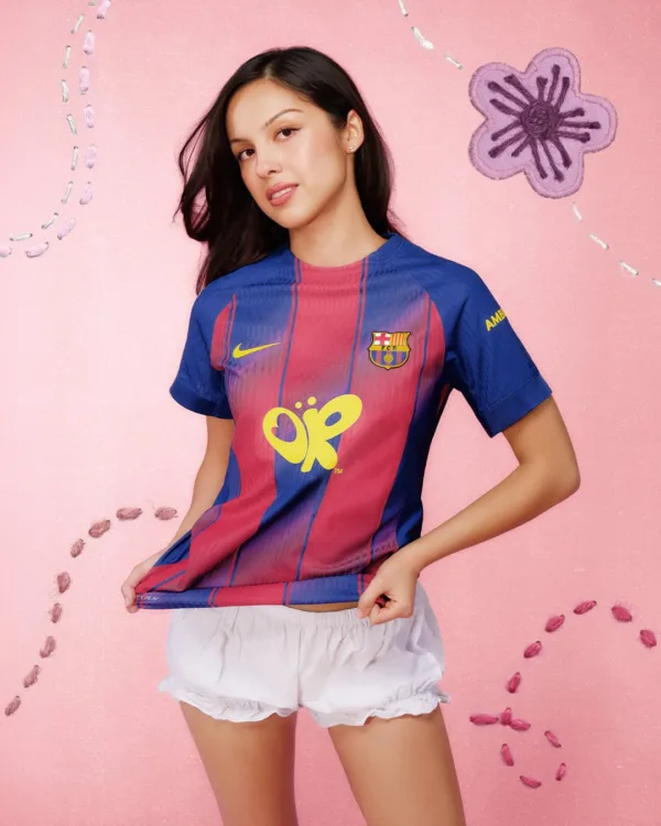 Η Olivia Rodrigo με φανέλα της Μπαρτσελόνα σε ροζ φόντο.