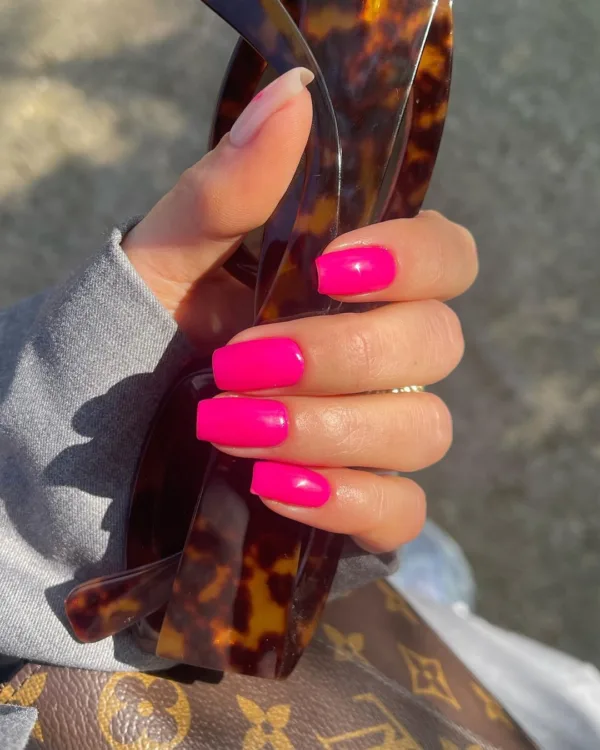 Χέρι με έντονα ροζ Popsicle Nails και γυαλιά ηλίου με ταρταρούγα, ιδανικά για το καλοκαίρι.